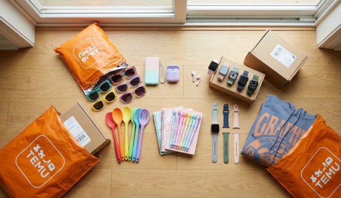 Top-down view of a diverse Temu shopping haul featuring fashion accessories, smartwatches, colourful kitchen utensils, and electronics, arranged on a wooden floor next to iconic orange delivery parcels